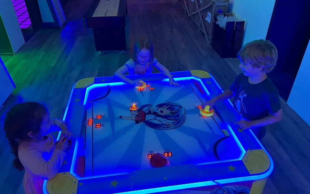 Kinder spielen zusammen Airhockey in der Action Alley