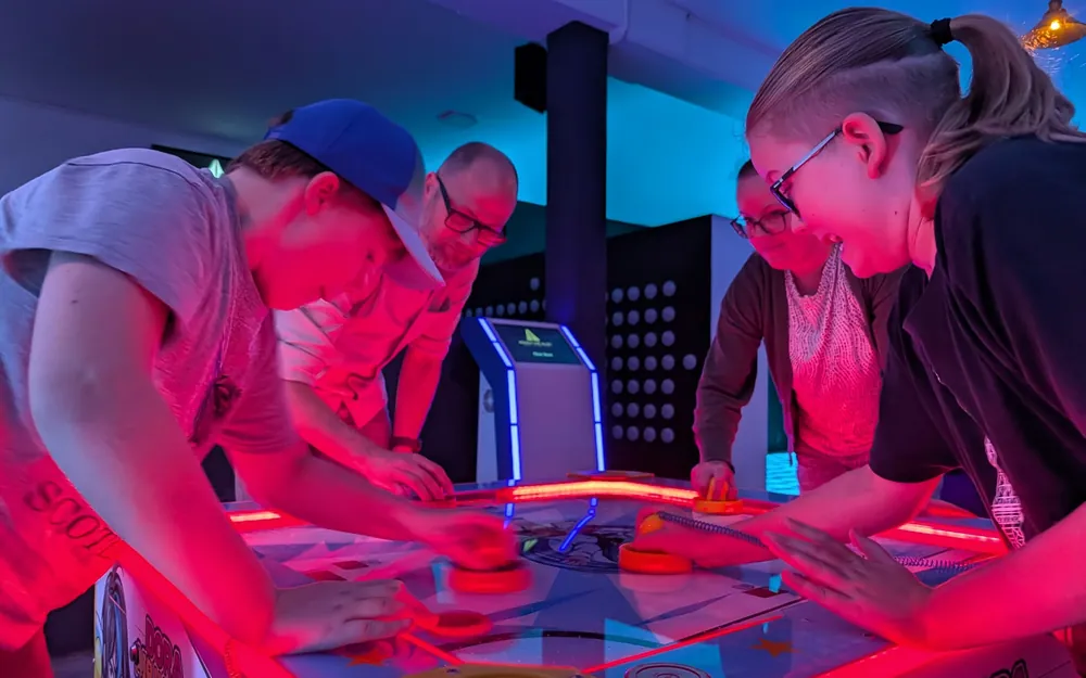 Kollegen spielen gemeinsam Airhockey in der Action Alley