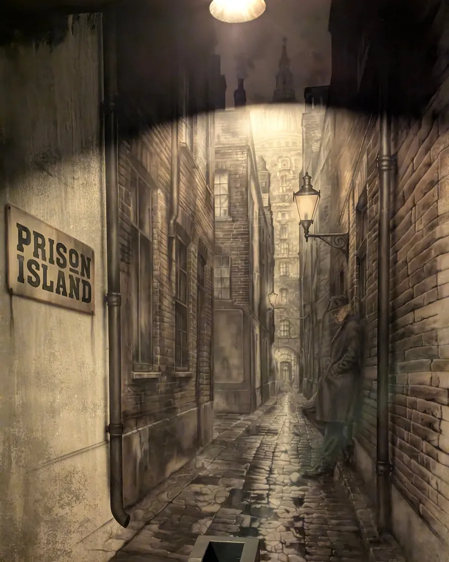 Eingang zu Prison Island: Treppe und beleuchtete Gasse mit Prison-Island-Schild